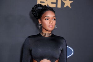 Janelle Monáe looking right wearing a black cutout dress and stacked black choker necklaces.