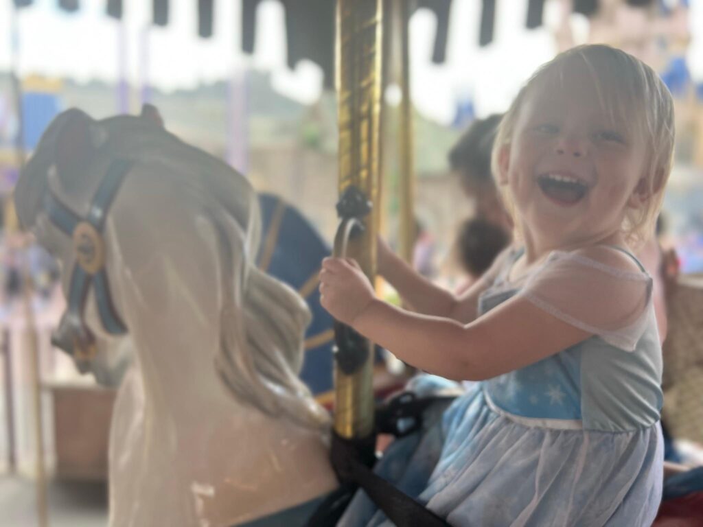 toddler smiles on a carousel ride at Disney World