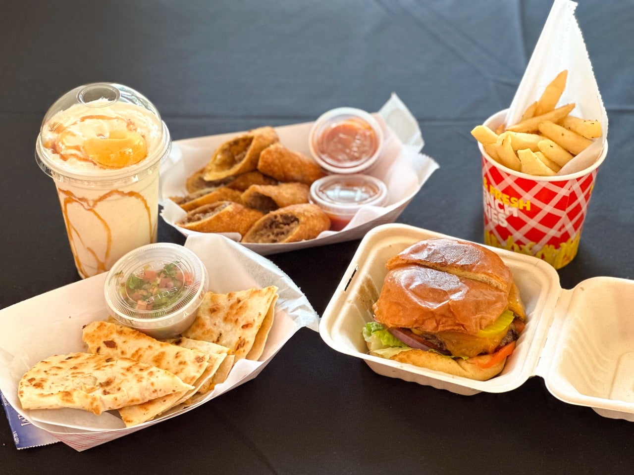 American Comfort food options at the 2024 Philadelphia Chinese Lantern Festival. Photo shows cheesesteak eggrolls, a quesadilla, a burger, french fries and a milkshake.